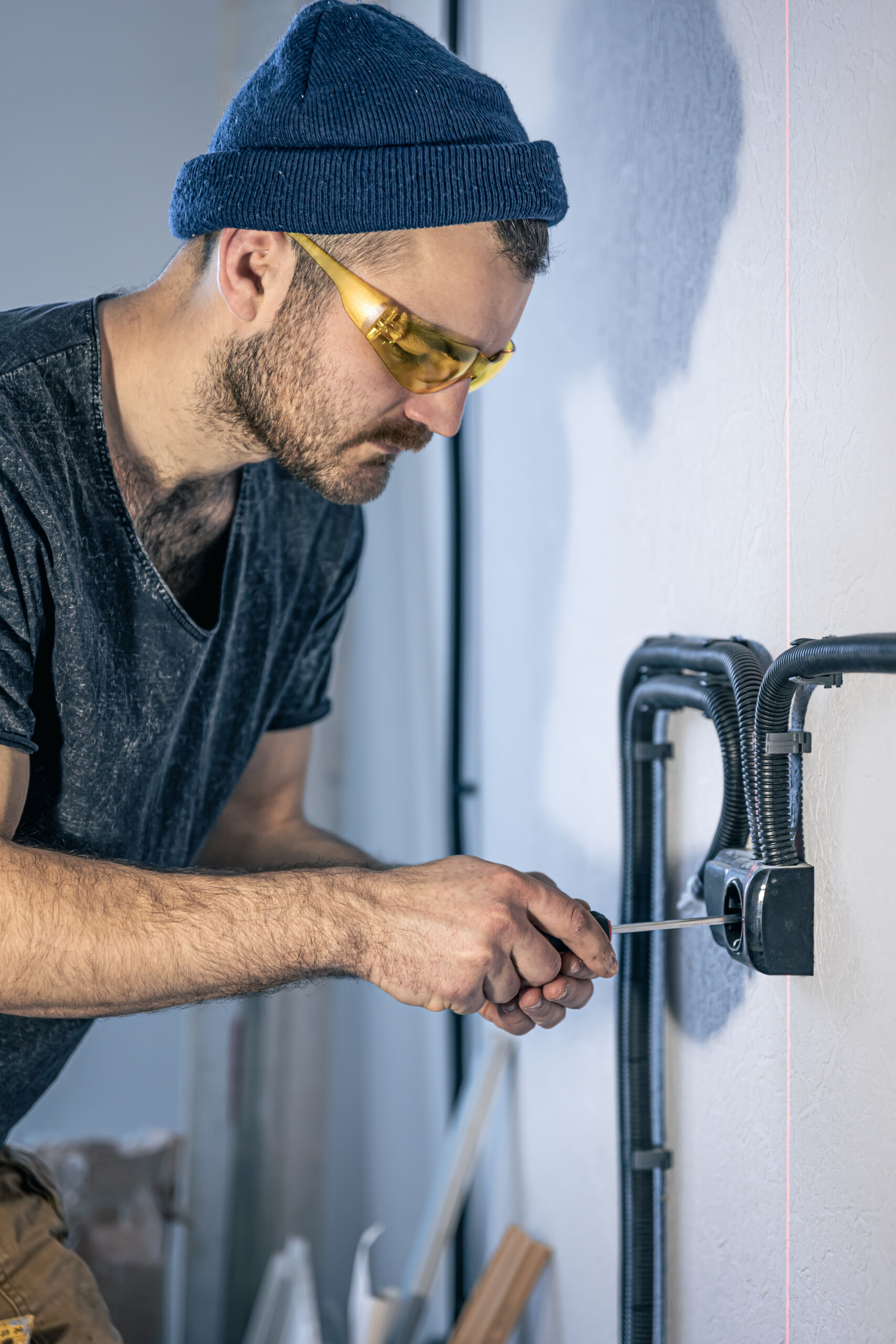 Attractive male electrician repairing an outlet, installing an outlet indoors.